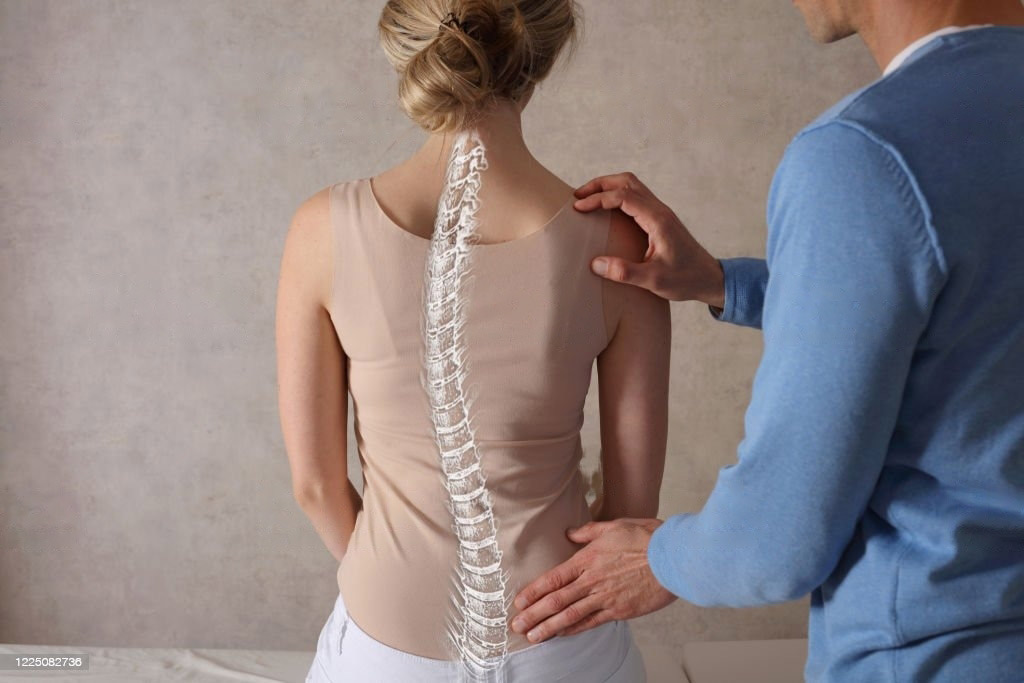 Doctor with hand on client's low back feeling the spine - Lighthouse Chiropractic and Wellness